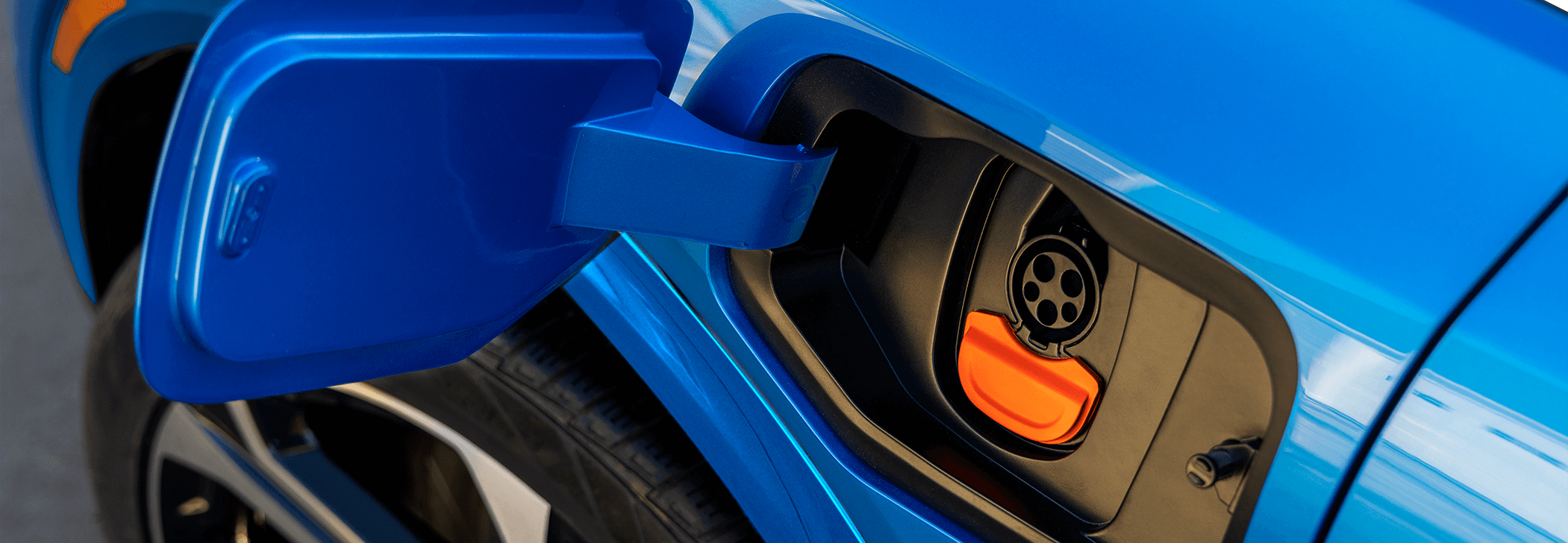 Detailed view of a blue electric vehicle with a charging station, highlighting its modern features.